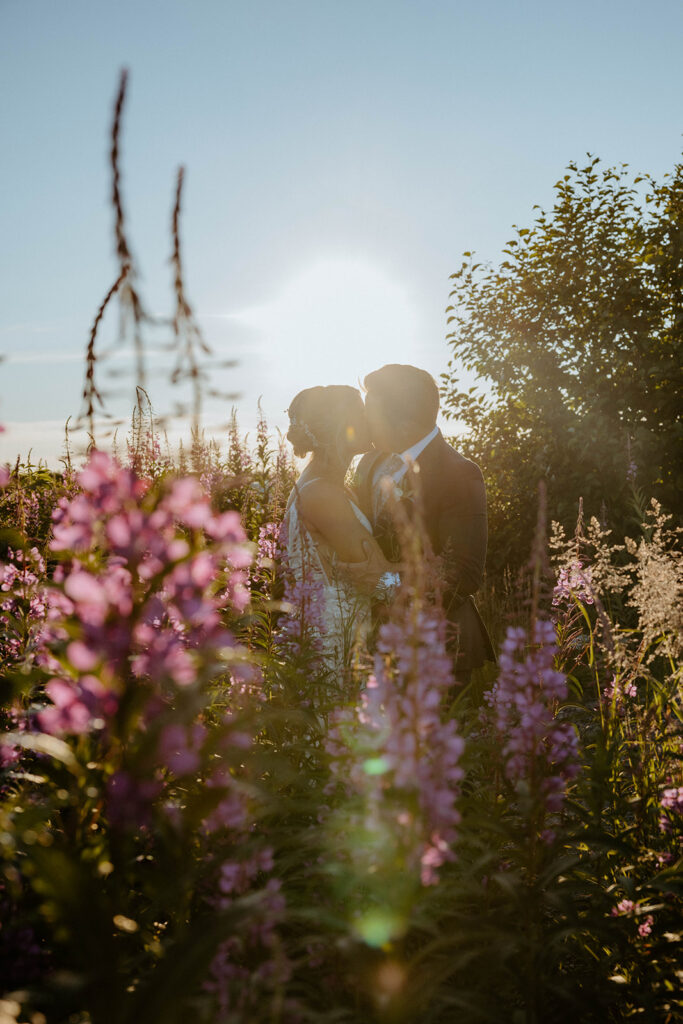 Bride and Groom kissing in fireweed blooms.